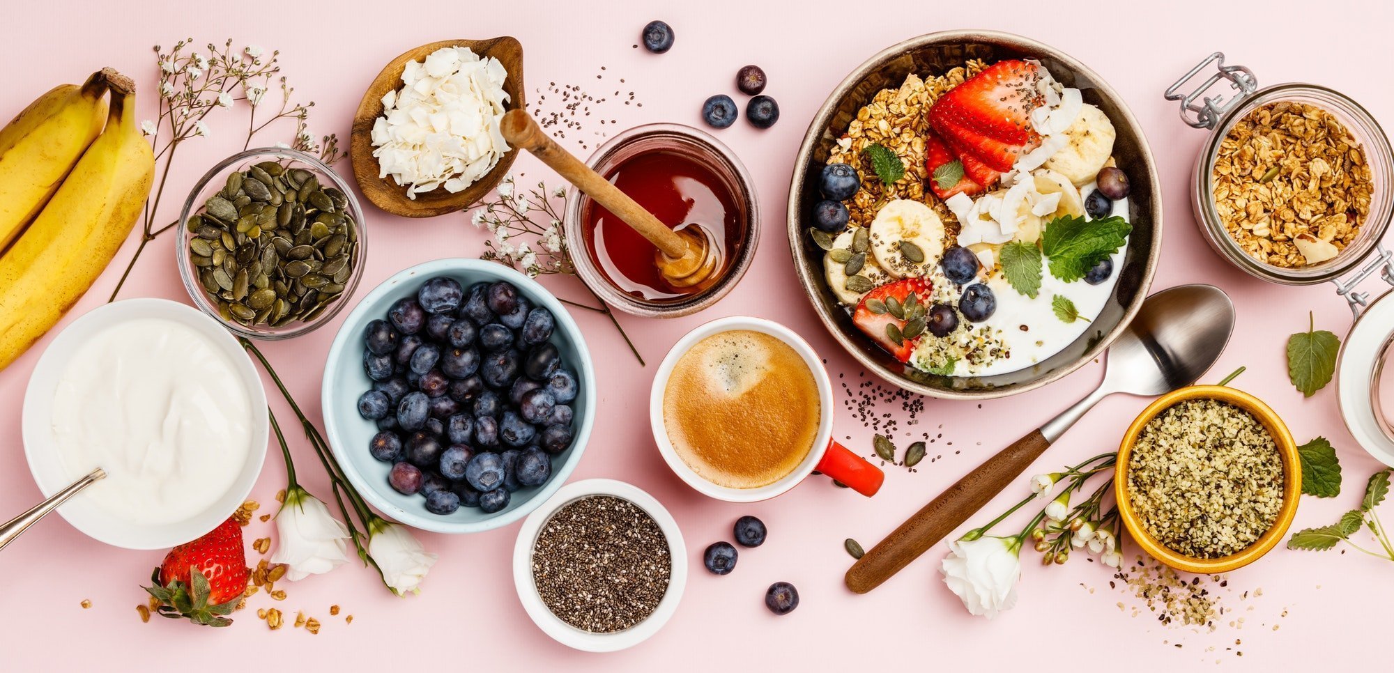 Frühstückstisch mit Beeren, Joghurt, Granola, Honig und Kaffee